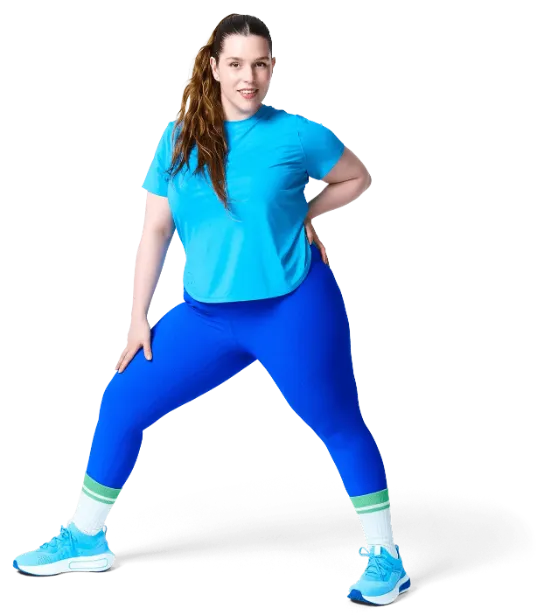 A person in sportswear is lifting one knee while standing on one leg, showcasing a workout or stretching activity.