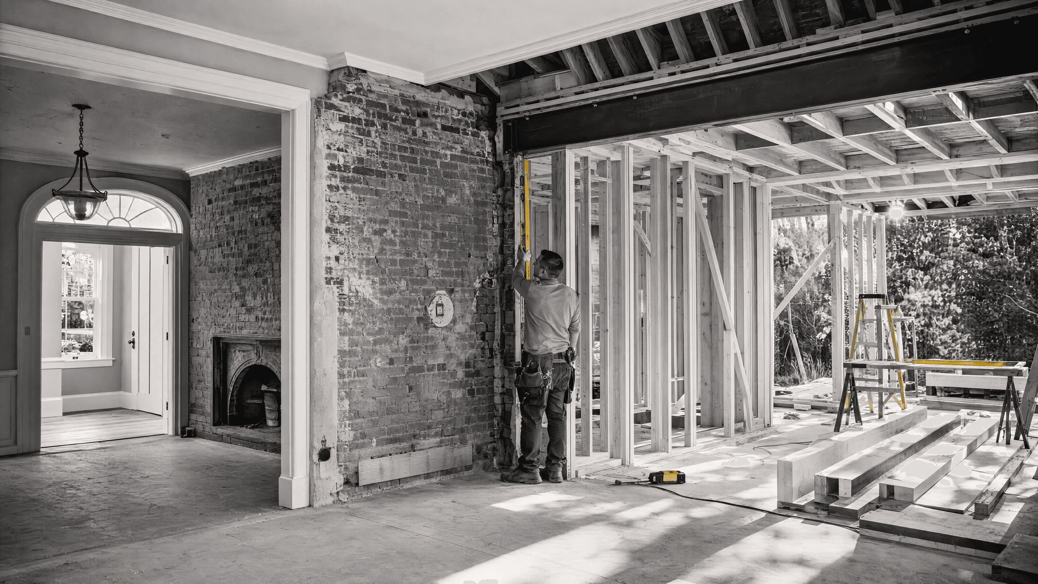 Retained brick wall and fireplace connected through a widened opening to newly framed construction during renovation.