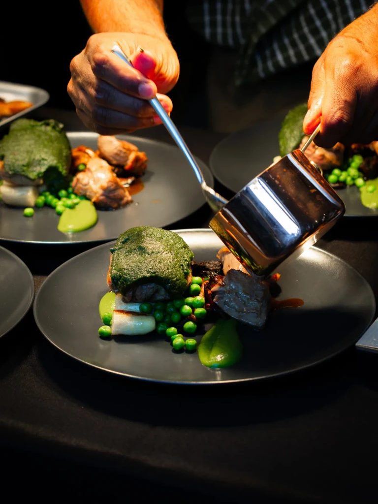 Sauce being added to a plated Herdwick lamb main