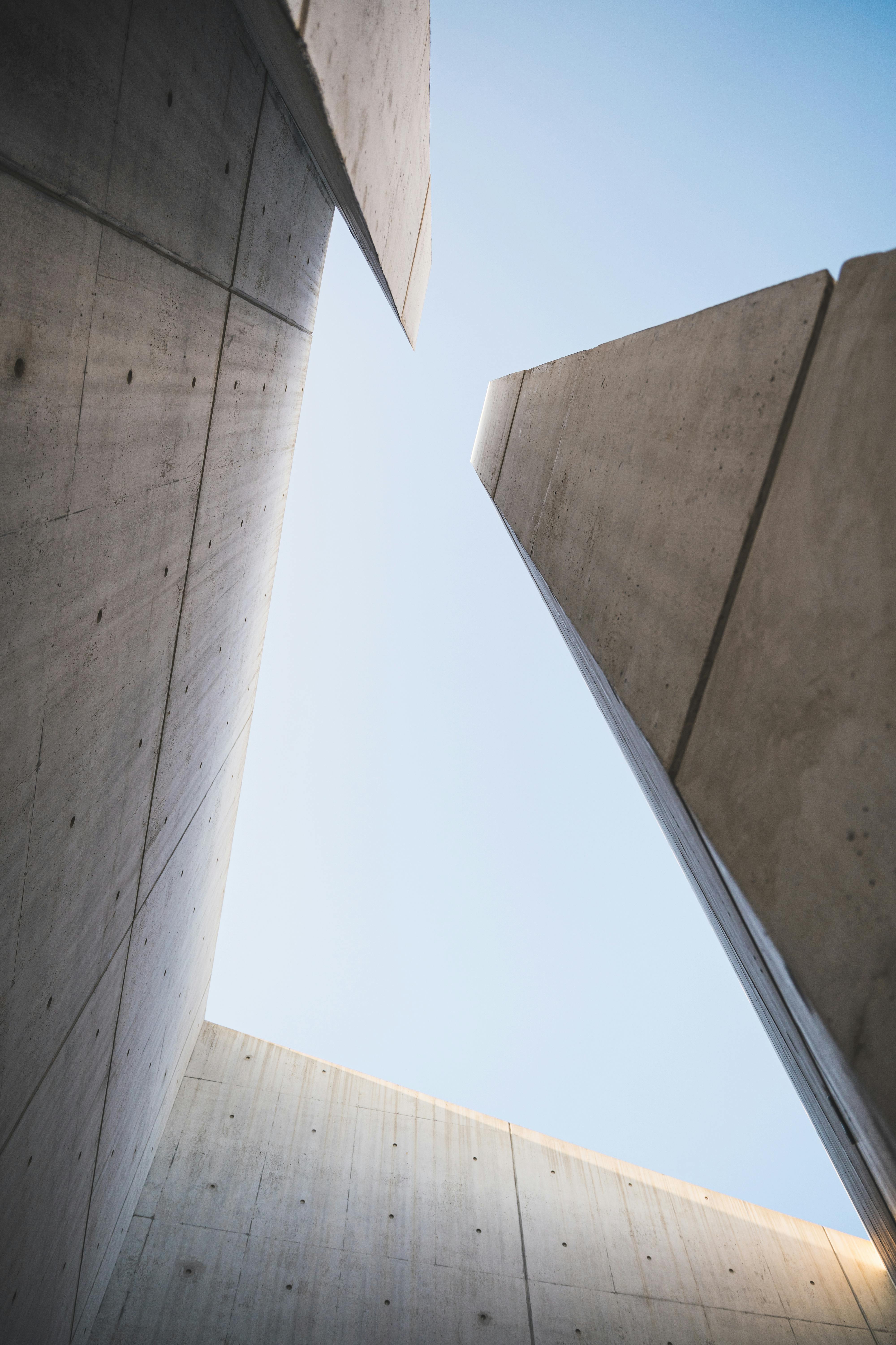 Smiling young woman with long hair standing against a dark green background, holding a finger to her chin.