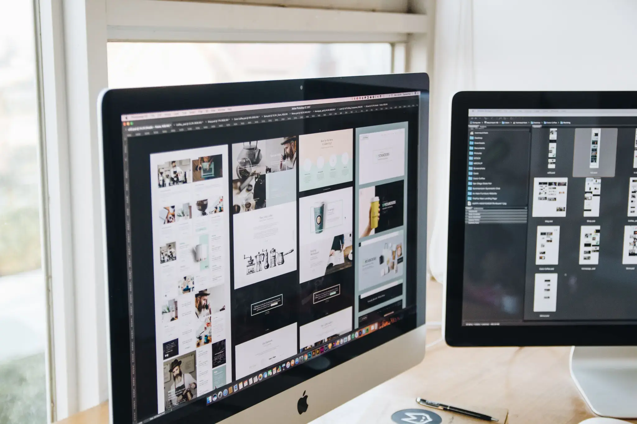 Dual-monitor workstation displaying website layouts and interface designs, illustrating professional web design and digital product development.