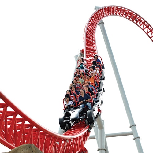 Isang grupo ng mga tao ang nakasakay sa isang pula na roller coaster, bumababa sa isang matarik na kurba, na may mga ekspresyon ng kasiyahan.