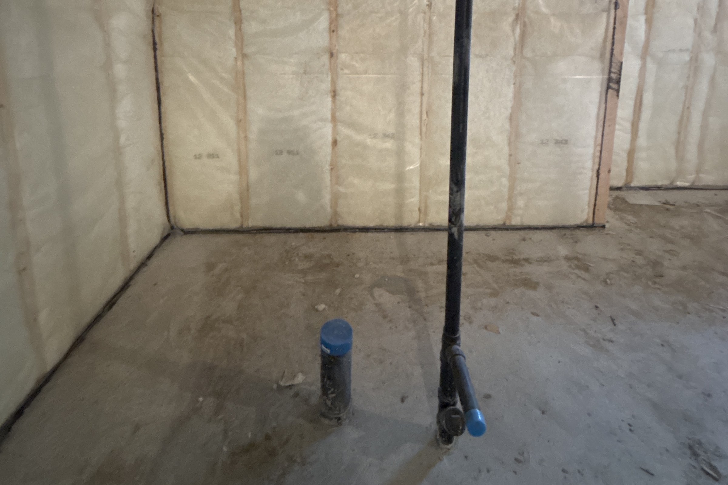 Unfinished basement before: plumbing rough-in and insulated walls where the bathroom now stands