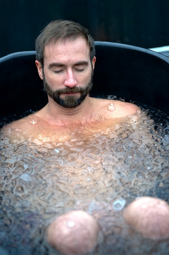 A man sitting calmly in an ice bath with his eyes closed