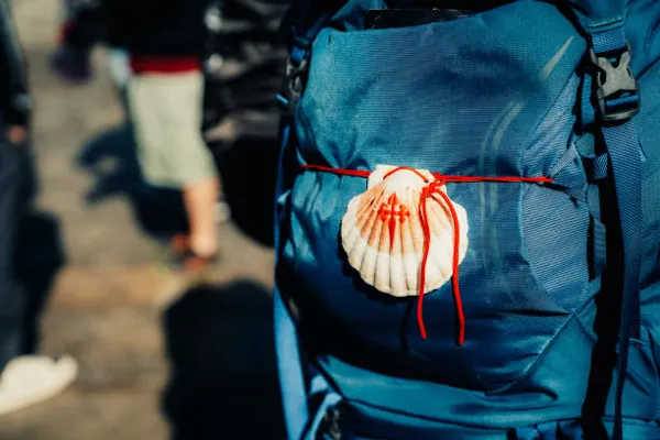 Mochila de peregrino com a vieira do Caminho de Santiago amarrada com cordão vermelho — apoio ao Caminho da Costa · Táxi Afonso · 11 Moledo e Cristelo