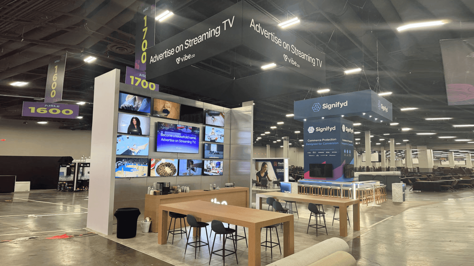 20x20 island booth with software demo screens, buyer meeting area, hidden storage, and open circulation