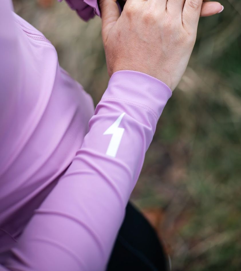 Close-up-of-the-sleeve-of-a-light- purple-long-sleeve-cyclin-top- showing-the-white-lightning-bolt- graphic-and-cuff-detail