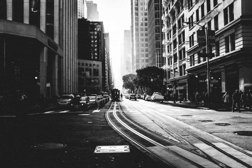 Black white image of a random suburban street with skyscrapers to each side in street view.