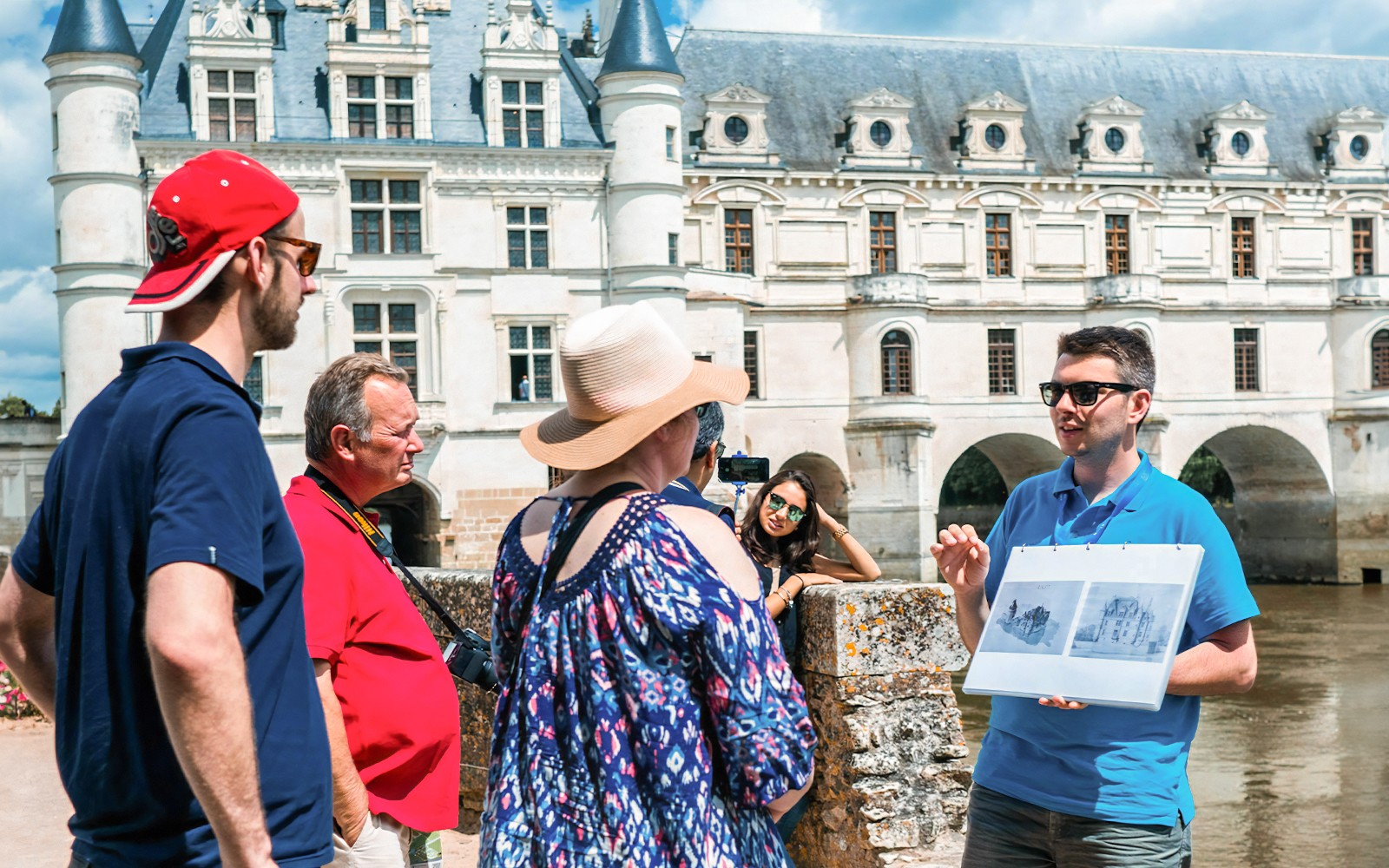 Guide explaining Chenonceau Castle to tour group in Loire Valley.