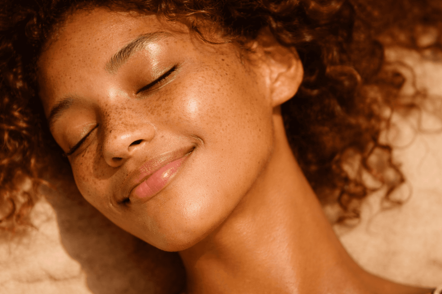 Portrait of a freckled woman with closed eyes in sunlight