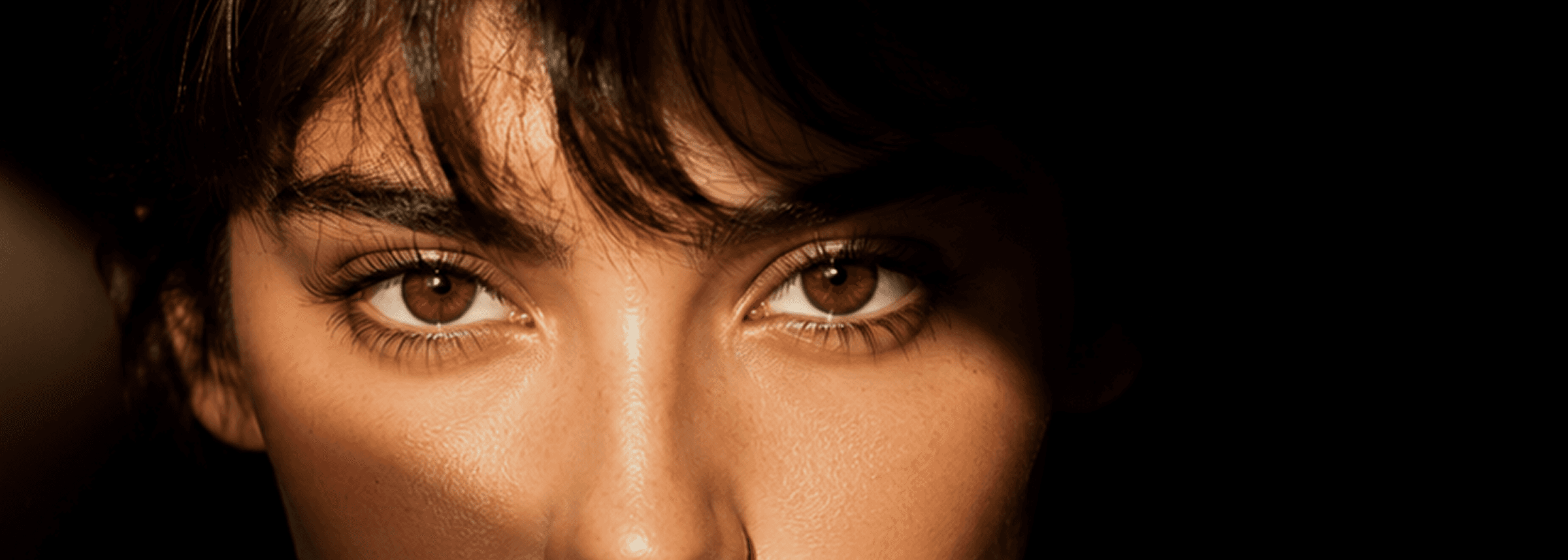 A woman with brown eyes gazes directly into the camera, showcasing a warm and engaging expression.