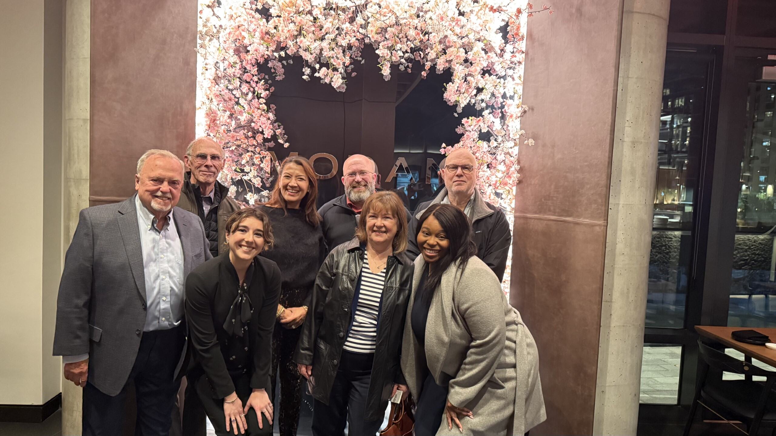 A person points at a computer monitor displaying a colorful graphic design in a modern workspace.