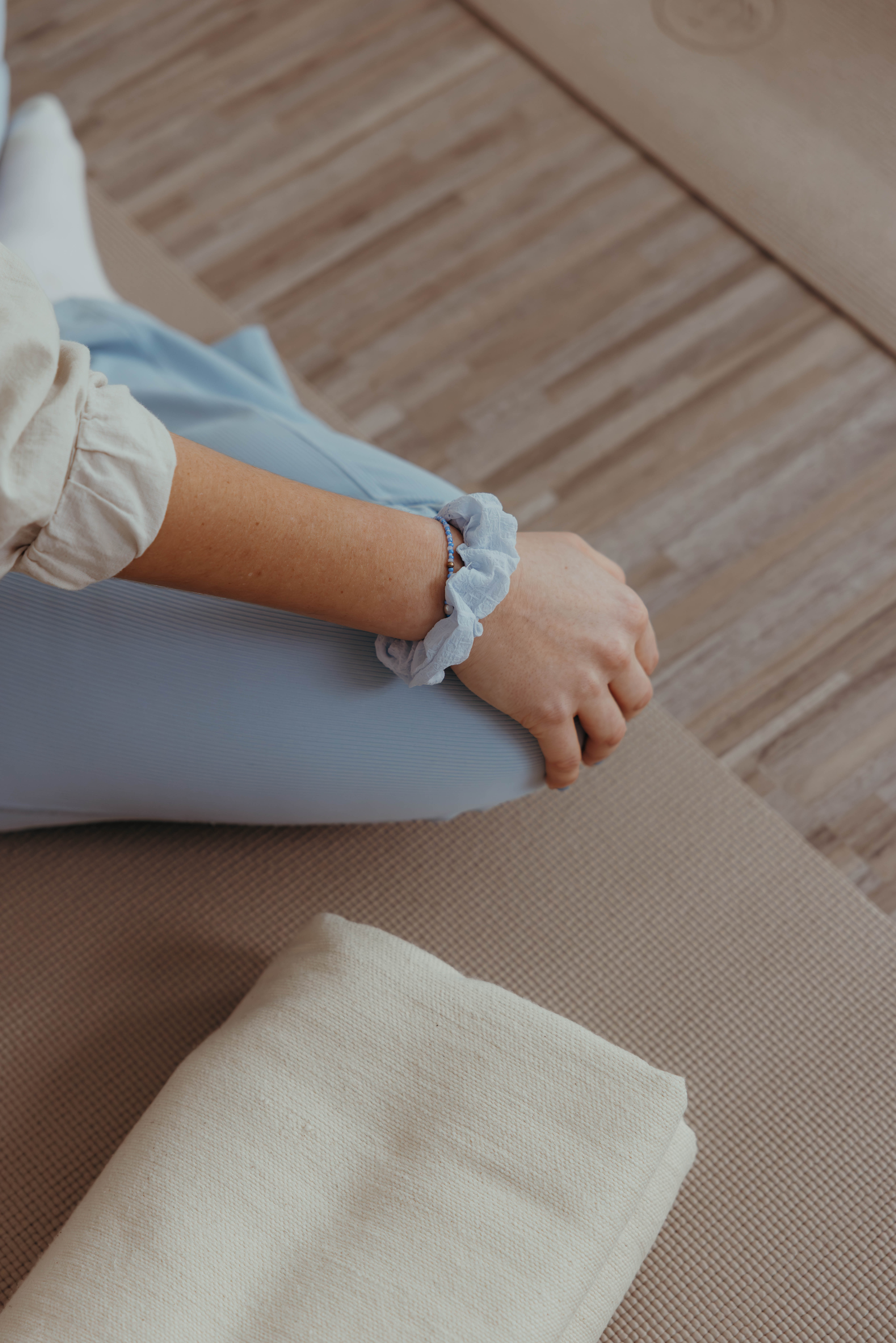 Person sitzt im Schneidersitz in einer Yogaklasse und folgt einer angeleiteten Übung.