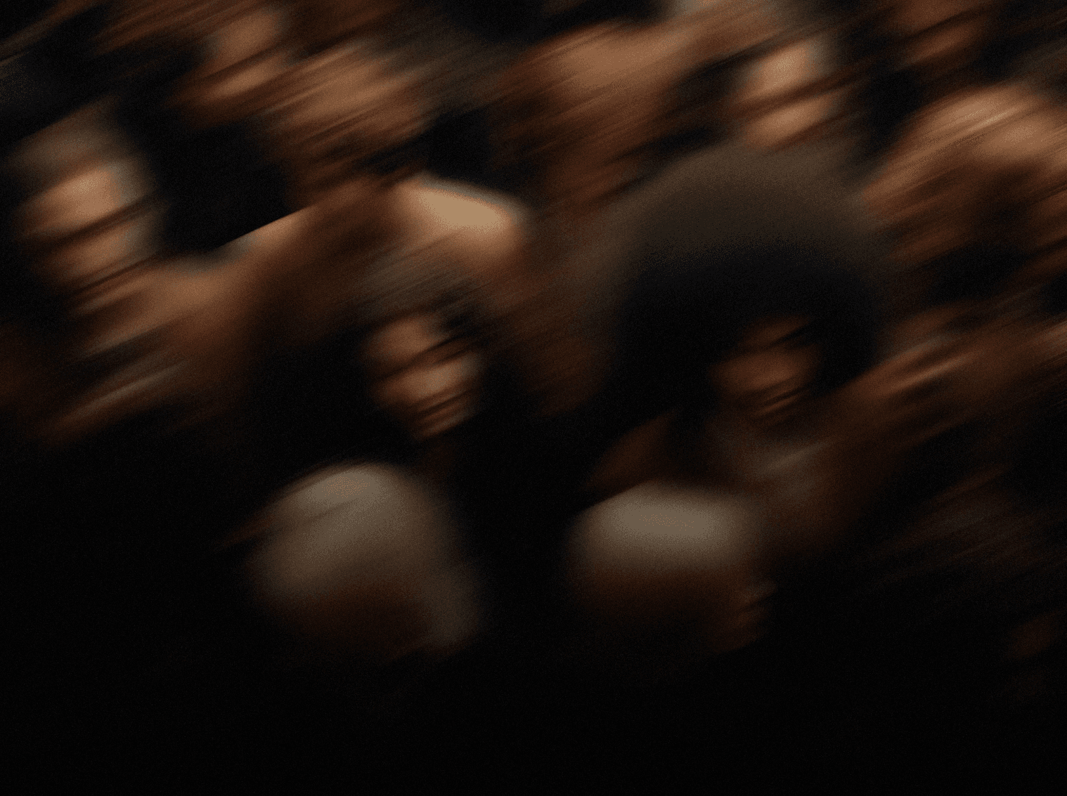 An abstract, motion-blurred crowd — faces merging into a wave of color and shadow, evoking movement, diversity, and the collective rhythm of humanity.  
