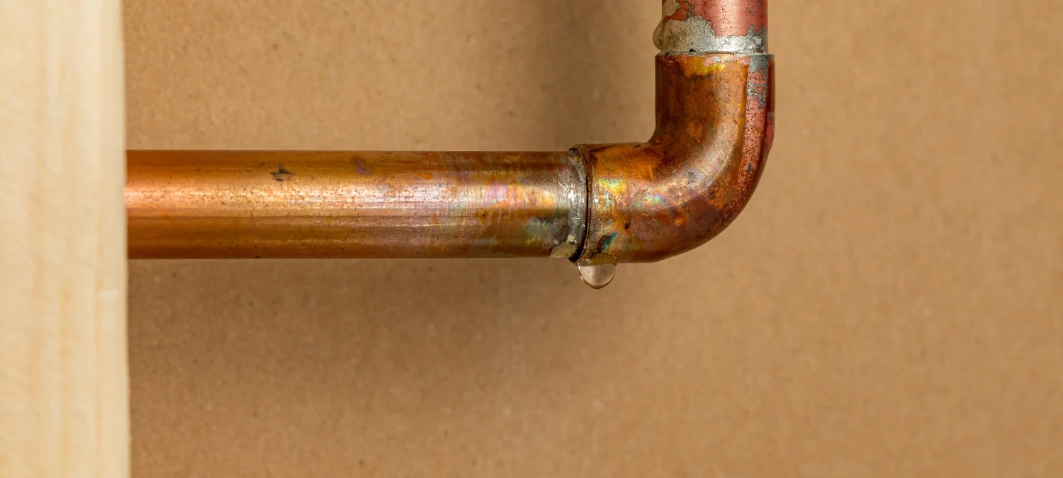 Close-up of clean copper pipe installation mounted on a wall.