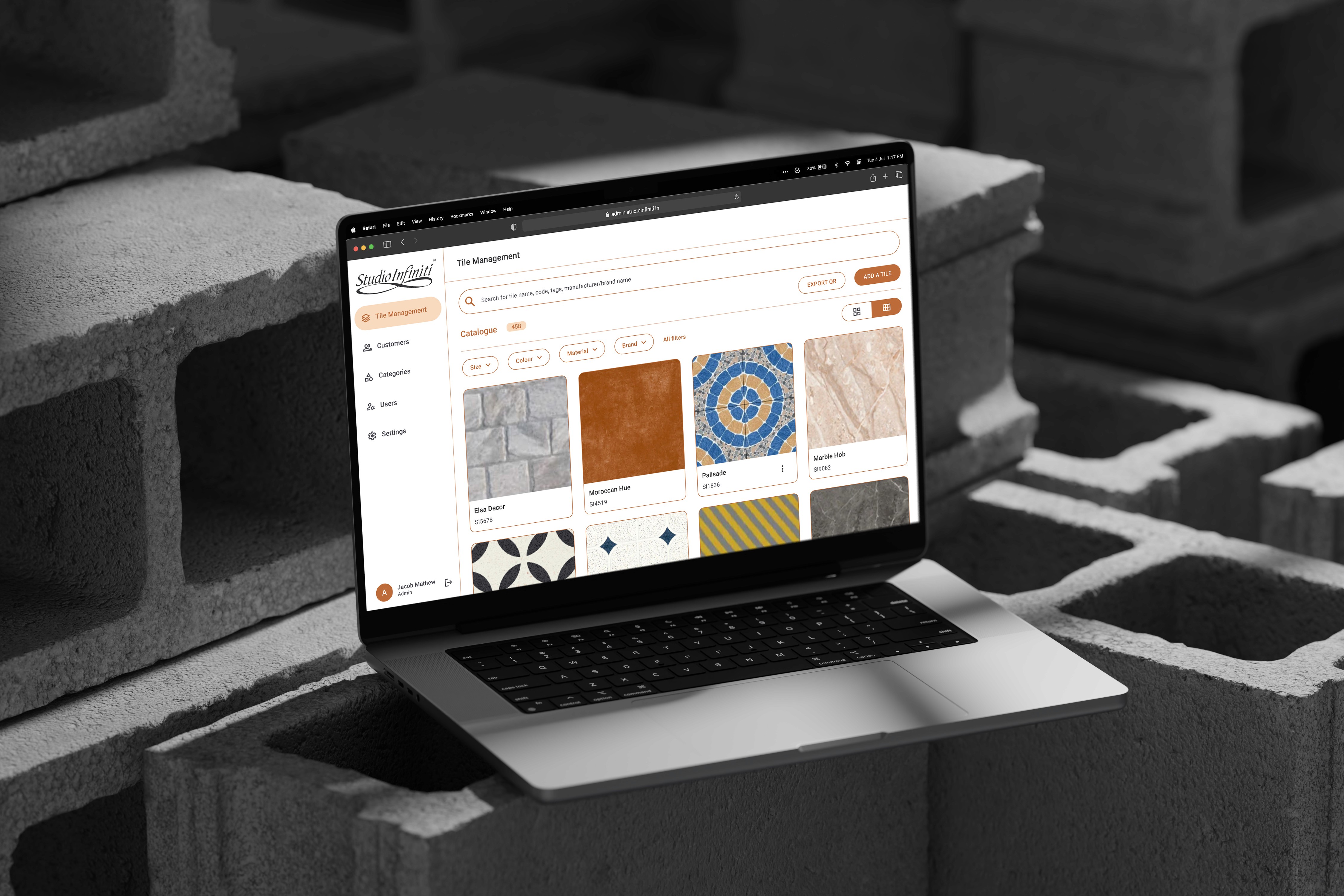 Laptop placed on concrete blocks, displaying tile design marketplace interface.