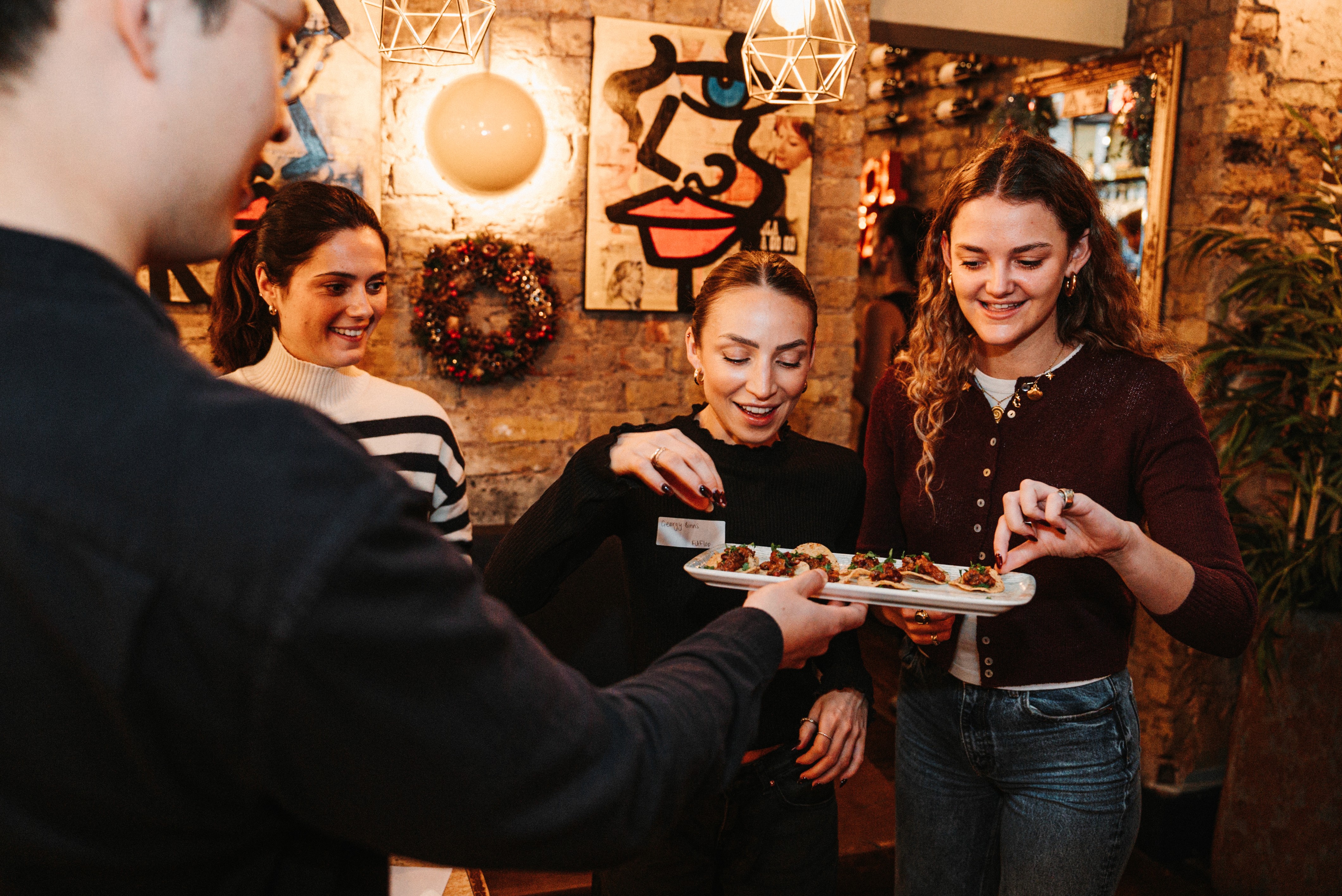 A PinPoint Media event where someone is serving food to three people.