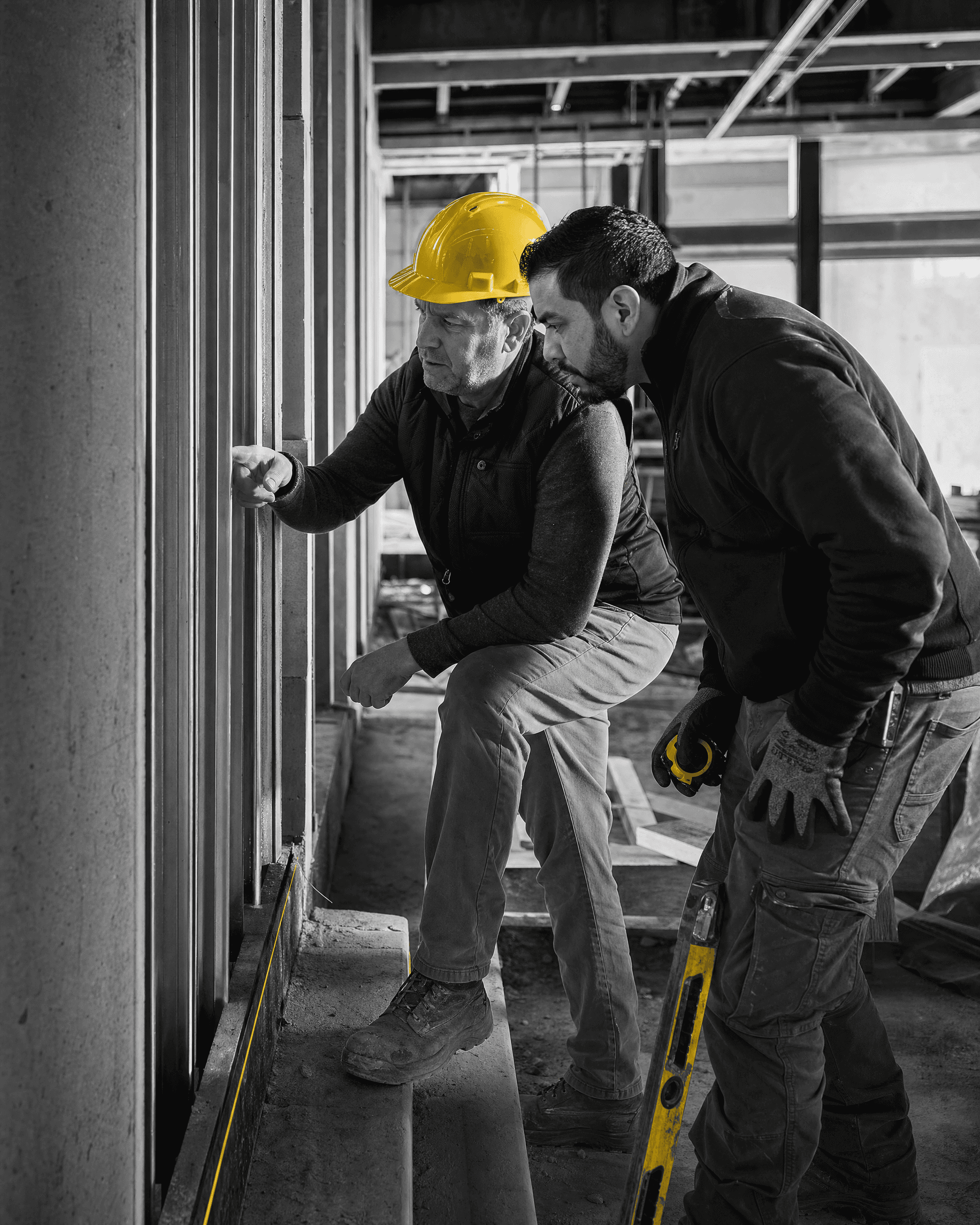 Construction project lead and skilled professional evaluating a framed wall condition together during an active renovation.