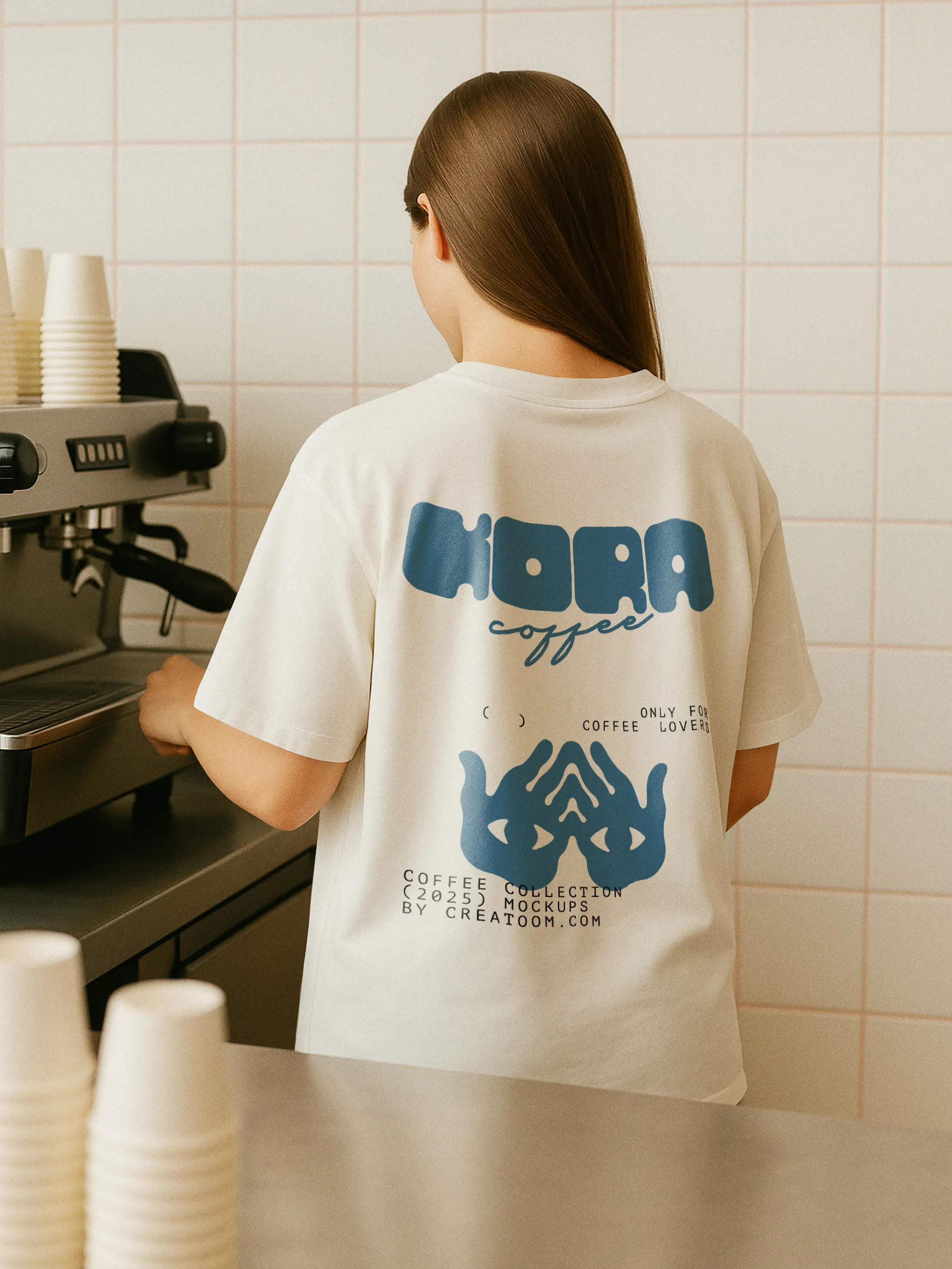 Barista wearing branded T-shirt at espresso machine with logo visible on back