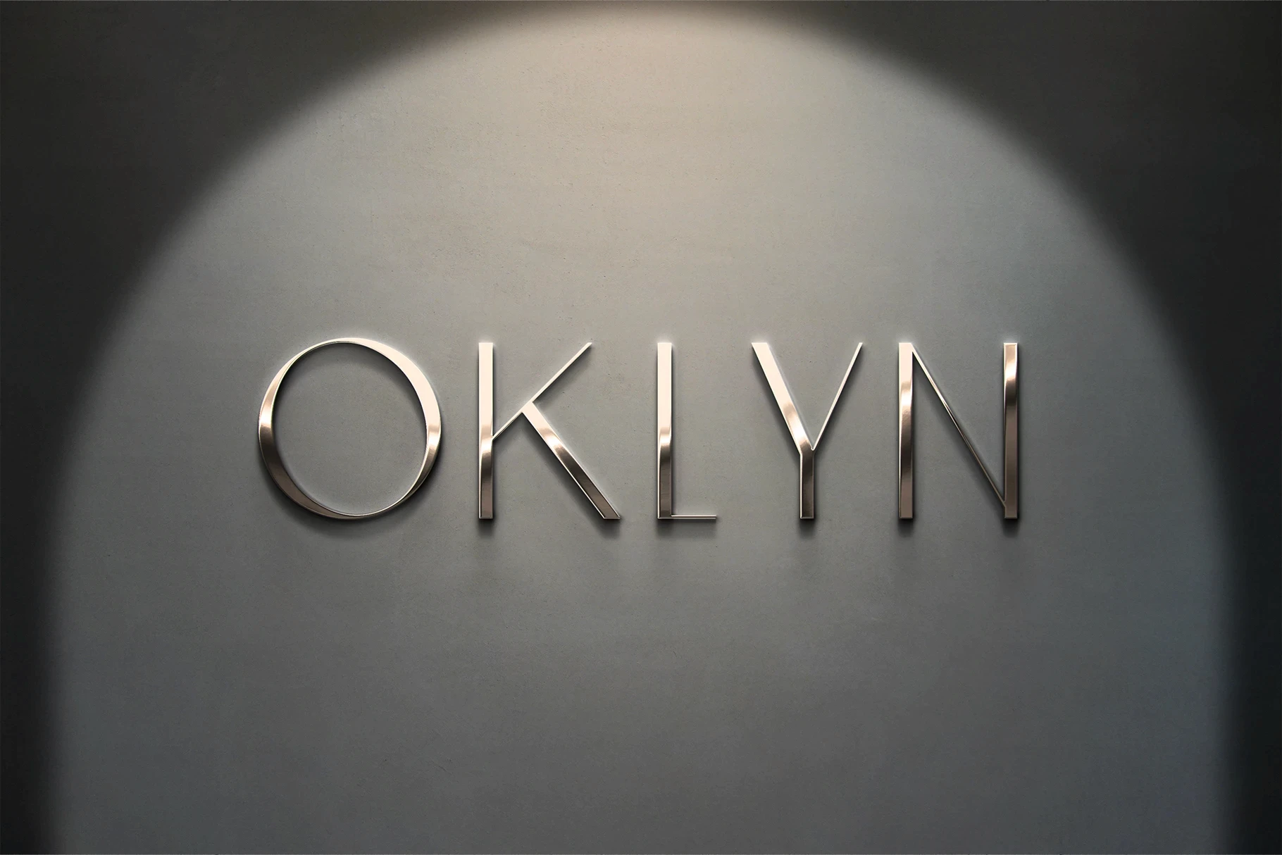 Deluxe 3D logo mockup with silver chrome letters on a wall with a spotlight.