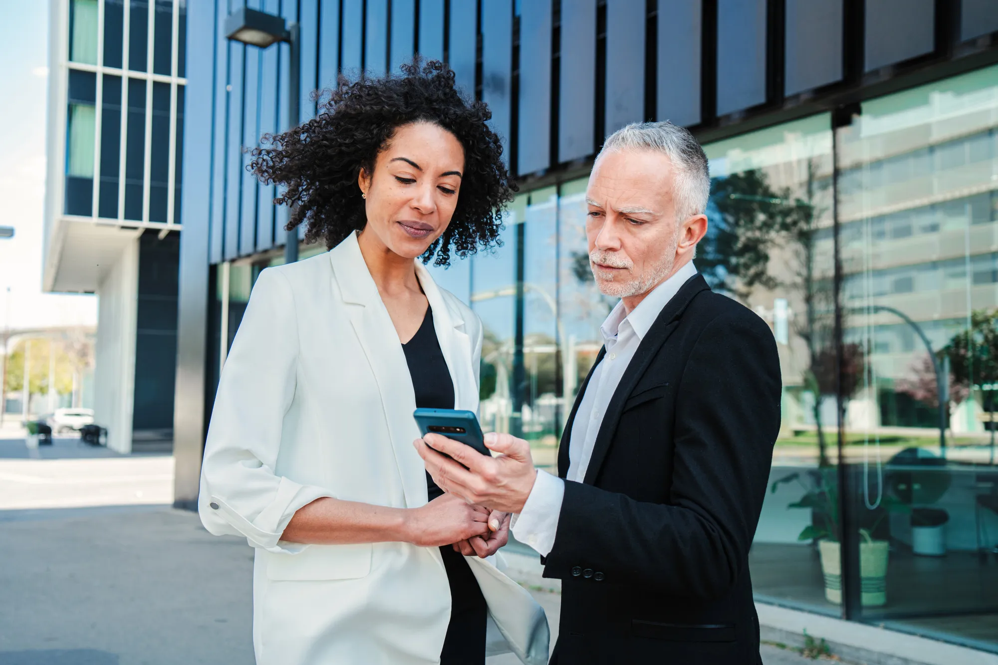 woman holding a phone and man looking at the phone. both are smiling