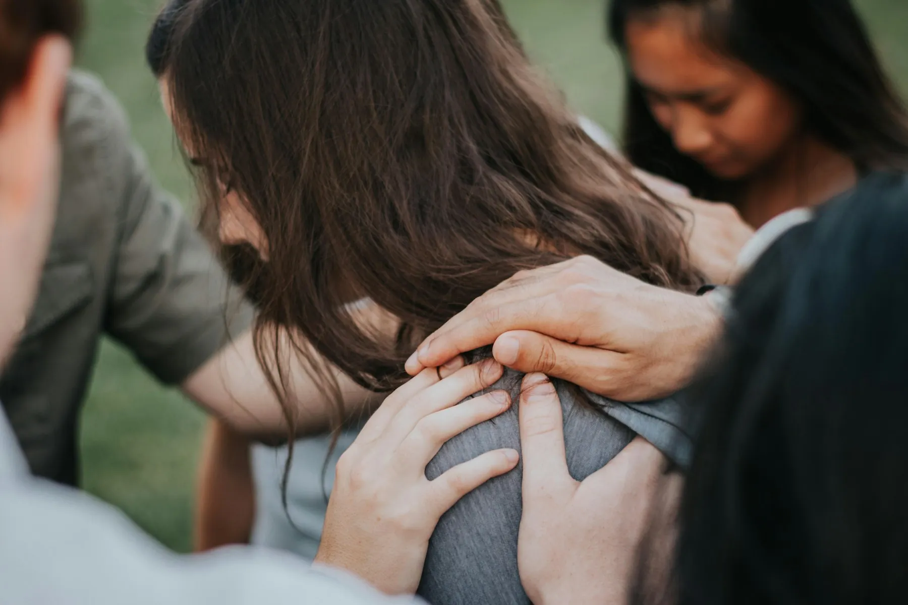 Hands resting on a friend’s shoulder in prayer