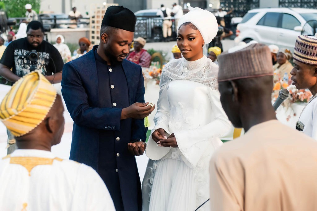 Luxury wedding planned by Victoria Brooks Events in Nigeria with elegant décor and beautiful reception. Groom in a blue suit and bride in a white wedding dress with flowers surrounded by family and friends.