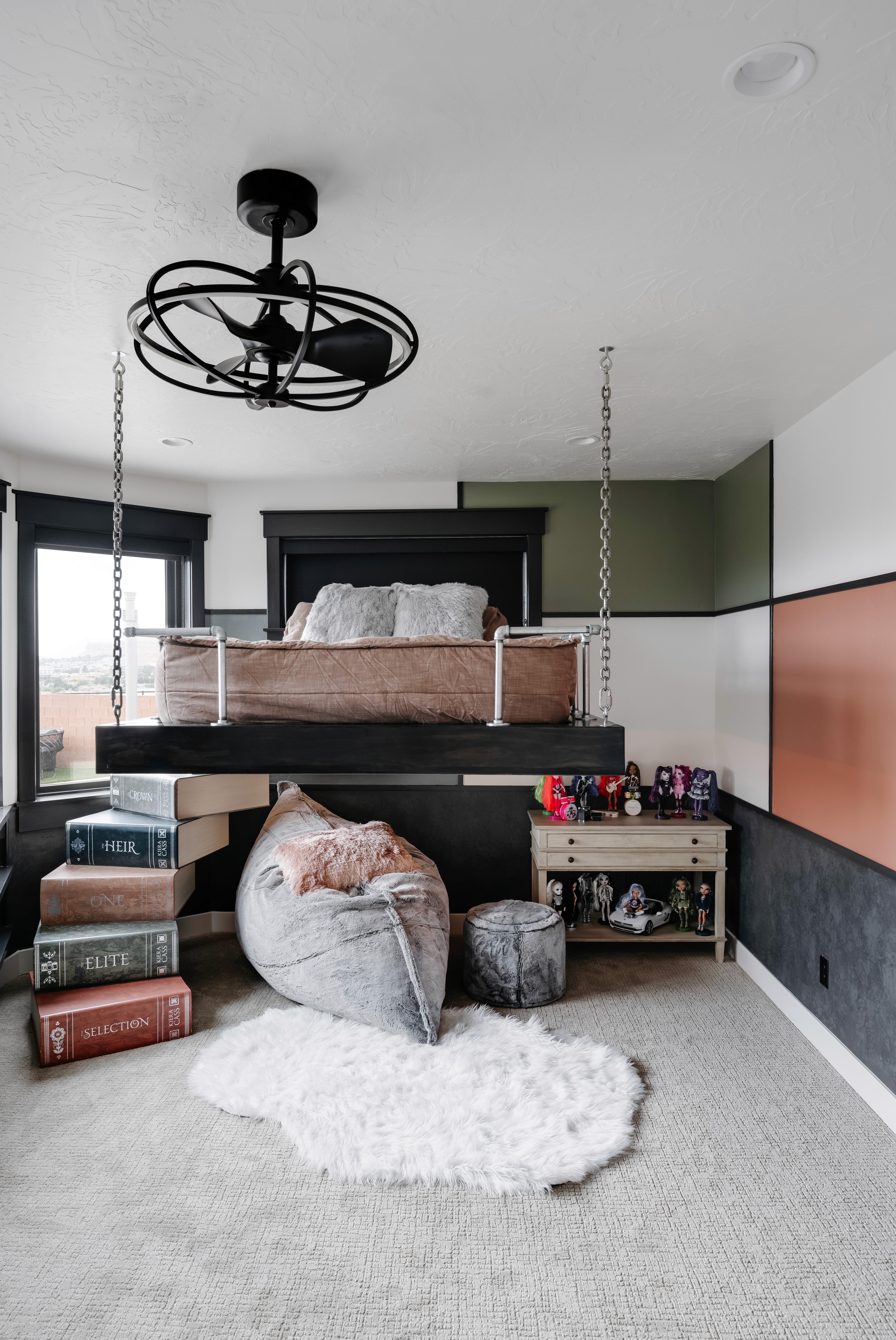 Bedroom with a raised bed, custom book staircase, and accent wall in a custom home in St. George, Utah.