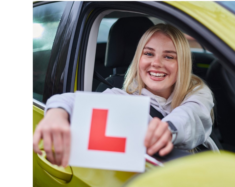Smiling learner driver holding L-plate in car after an its4women driving lesson in Ireland