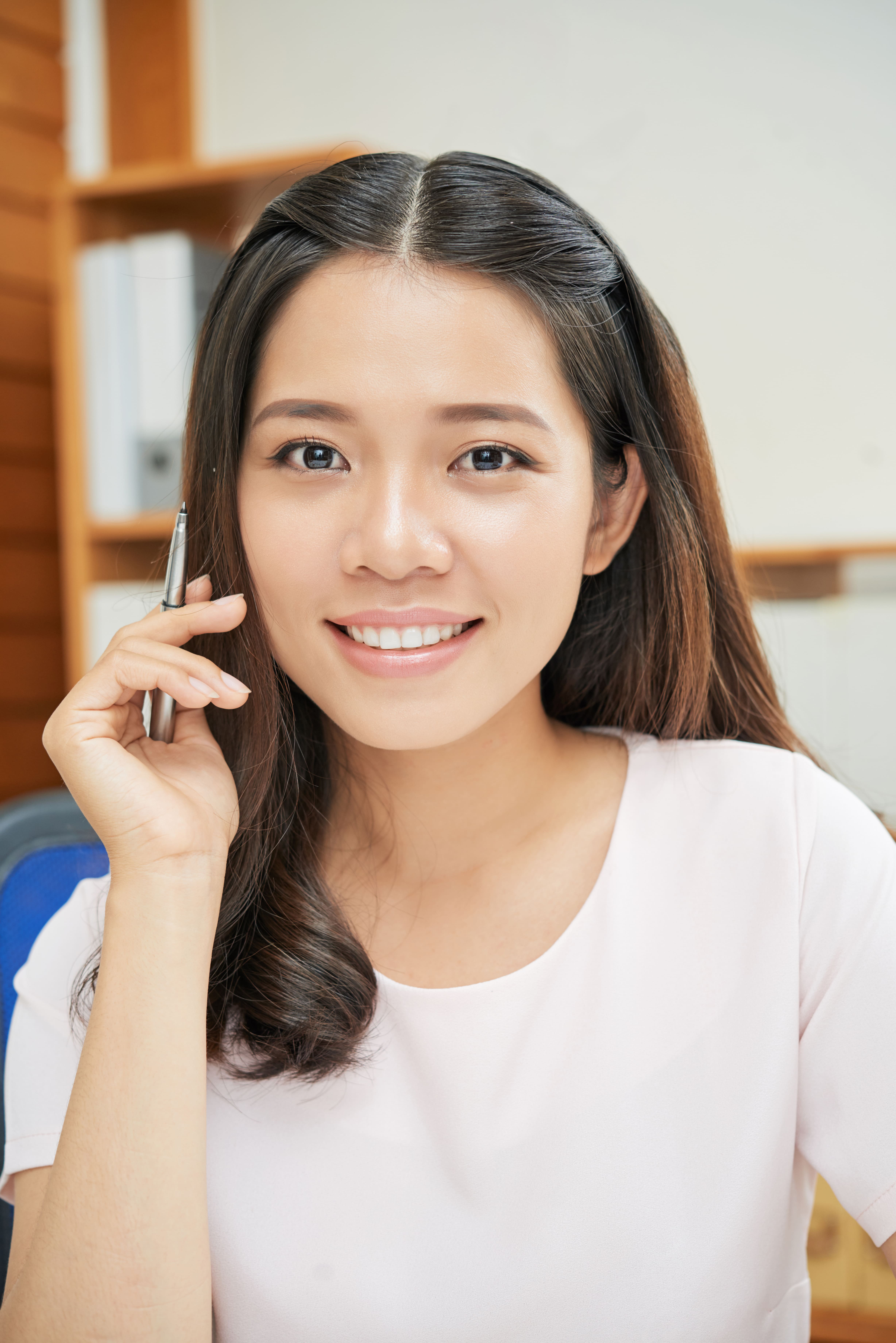 A smiling woman with long hair, holding a phone to her ear, engaged in a phone call.