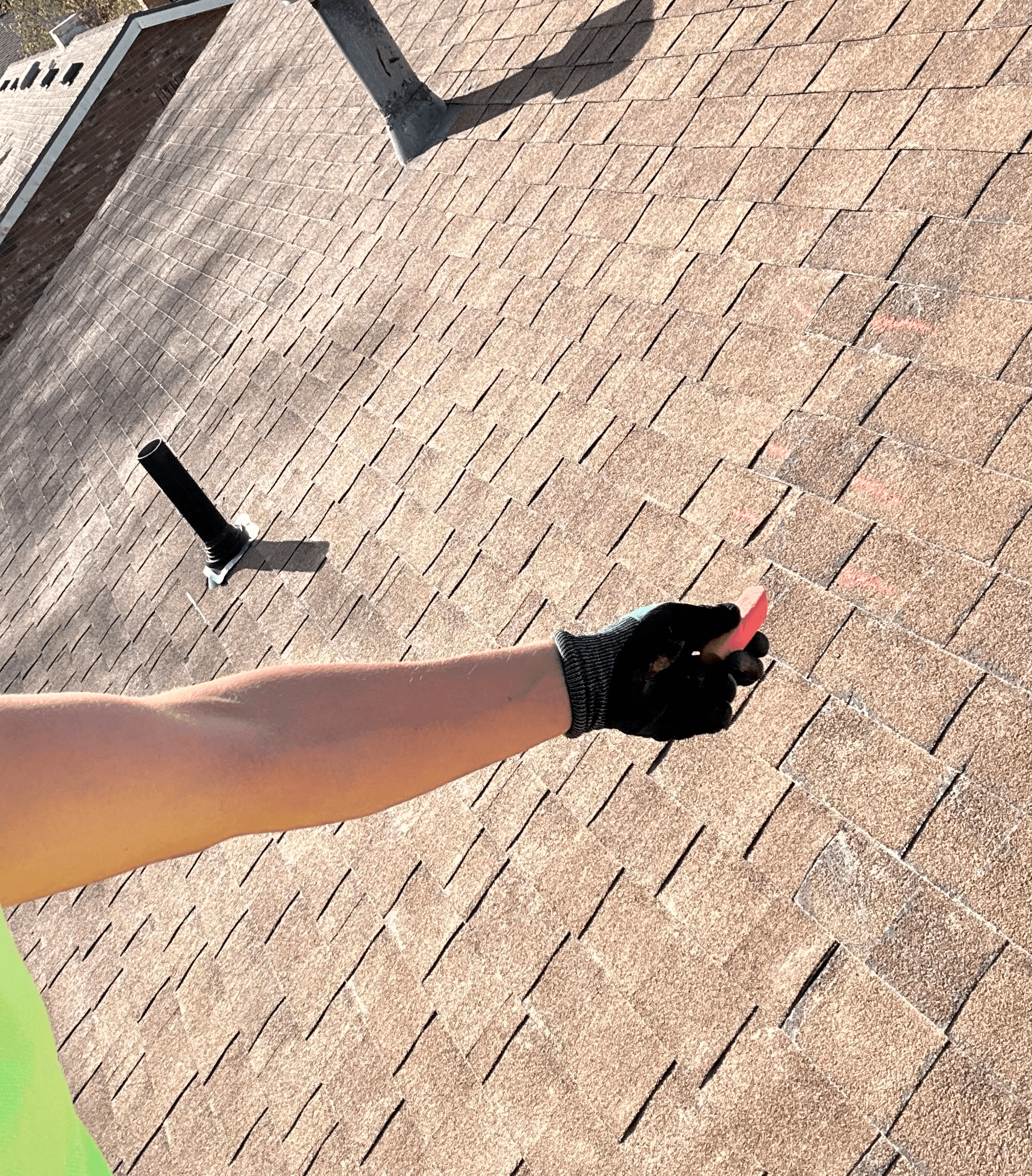 Roofer marking a shingle for repair during a roof inspection