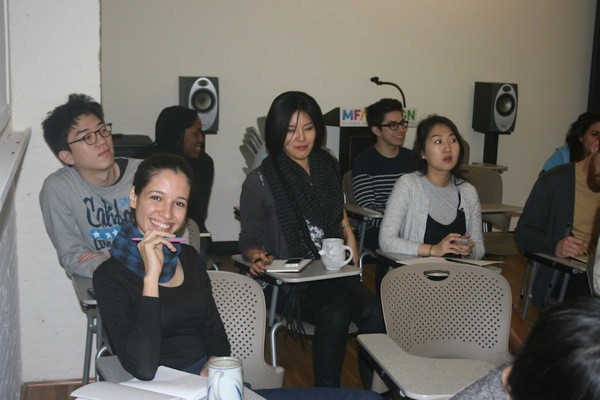 A photo of a group of students sitting in a classroom and following a lecture.
