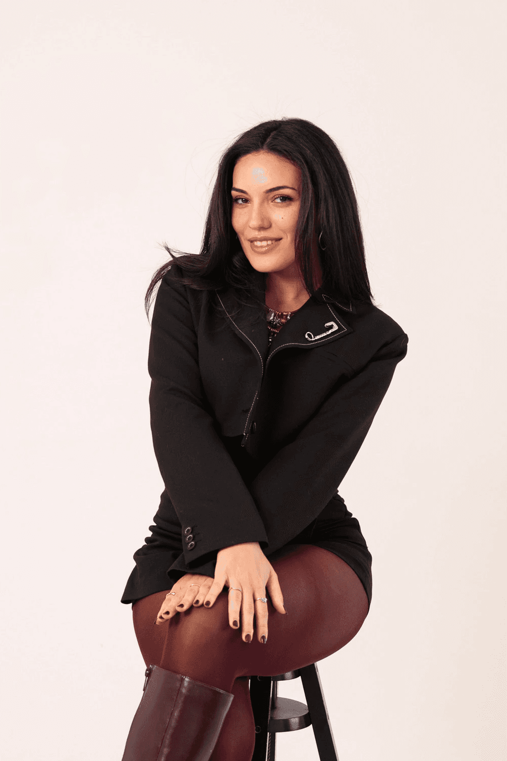 A young person with long, wavy hair sits in front of a plain background, looking directly at the camera.