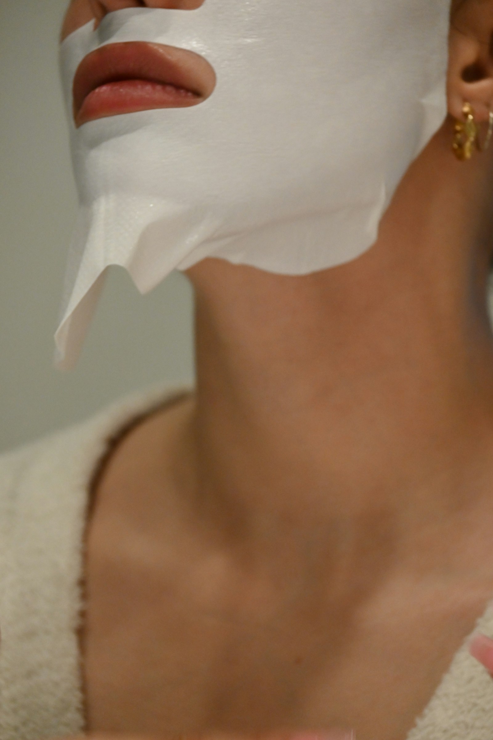 Profile view of a white sheet mask smoothed along the jaw