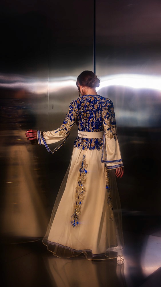 Ivory Moroccan caftan with deep blue embroidery, handcrafted couture piece combining Bahrain atelier and Moroccan artisans