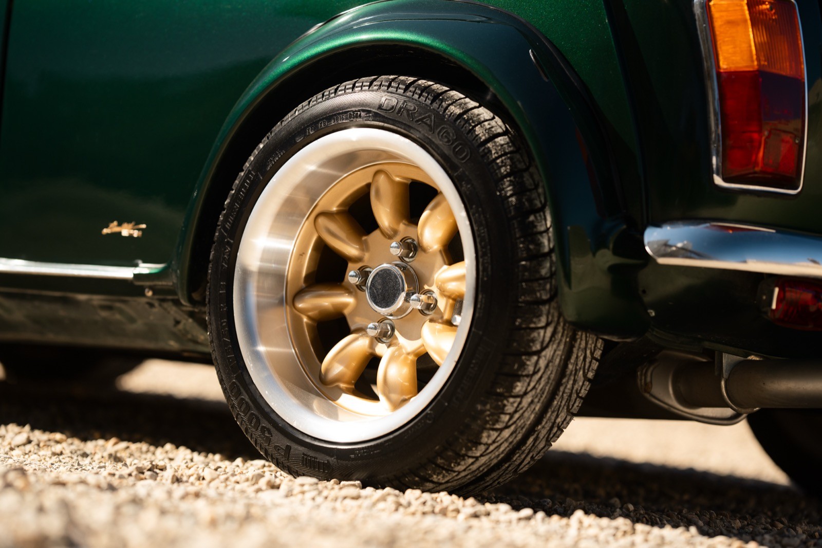 A small, green and black vehicle parked on a sandy surface, with a warm sunset lighting the scene.
