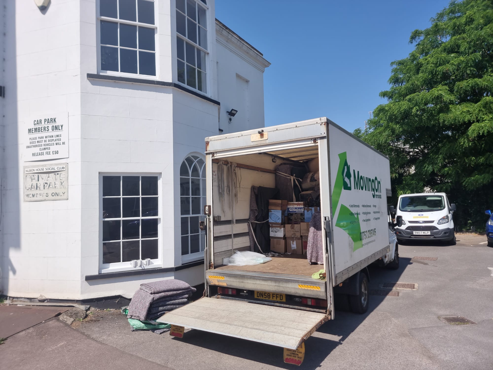 An open Moving On Removals van showing neatly stacked boxes and protective blankets during a house move to an apartment complex in Cheltenham.