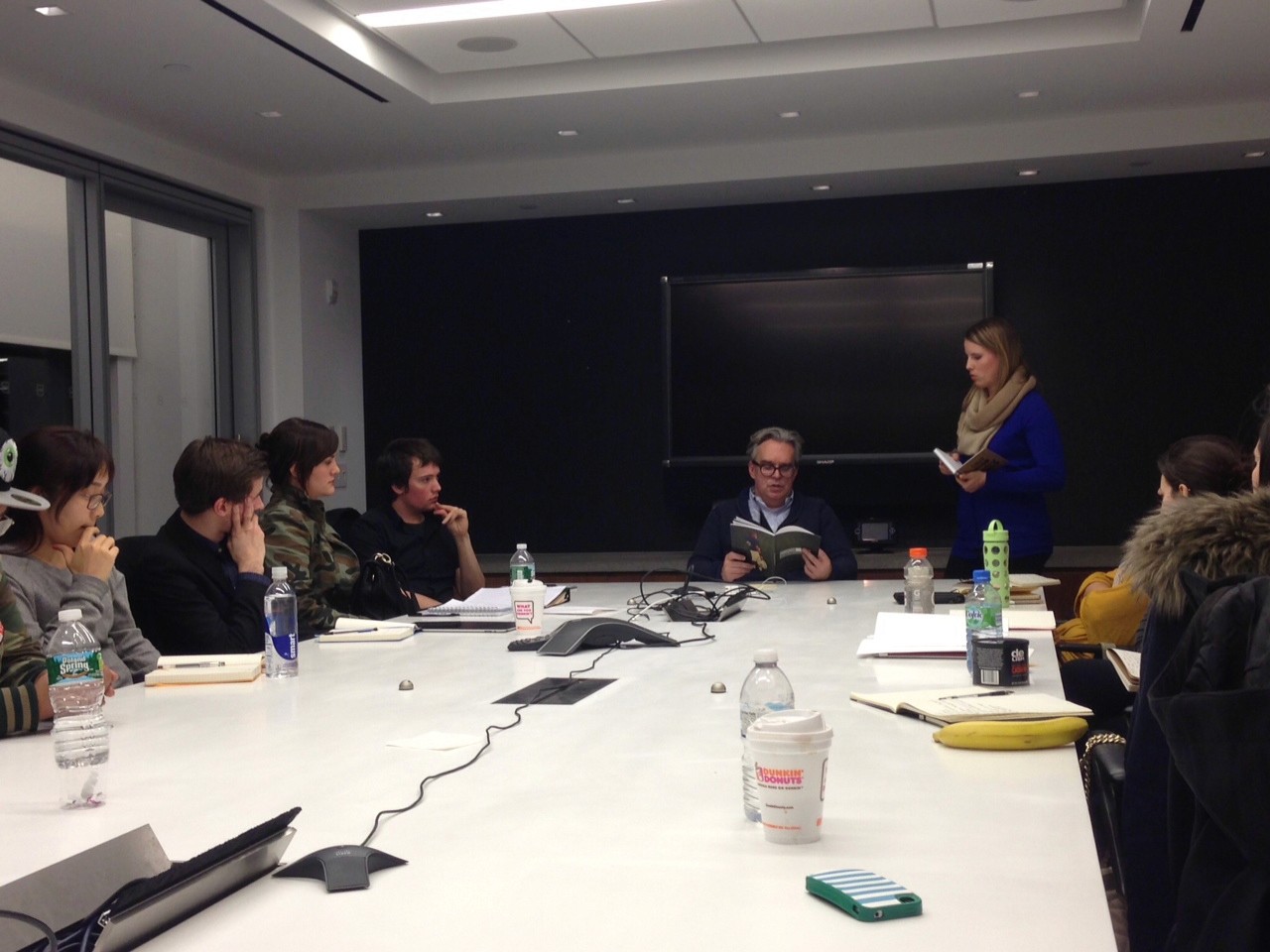 A photo of a group of people listening to a lecture while sitting at a conference table.