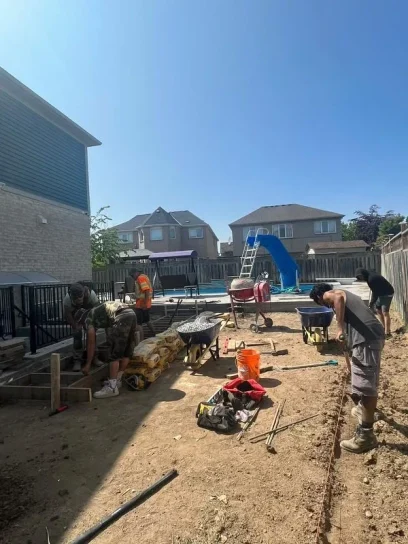 Workers preparing ground and materials for backyard construction near pool – Falcons Landscaping.