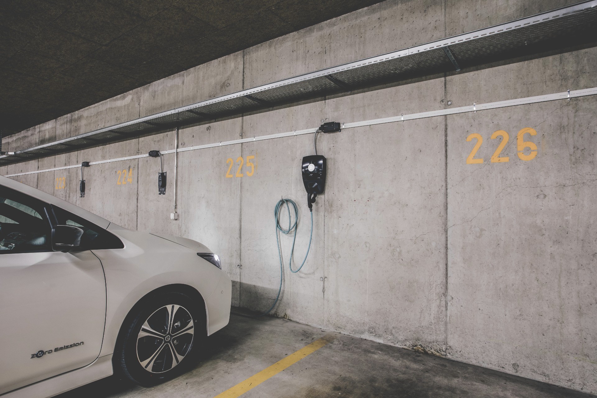 Stations de recharge pour véhicules électriques dans un parking intérieur, mettant en avant l'intégration des infrastructures de recharge pour soutenir l'adoption des véhicules électriques et la mobilité durable en Suisse.