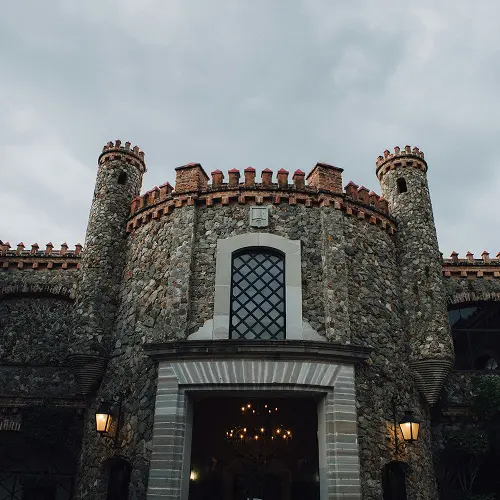 Grand stone arched entrance to Sudeley Castle with lanterns and historic architecture