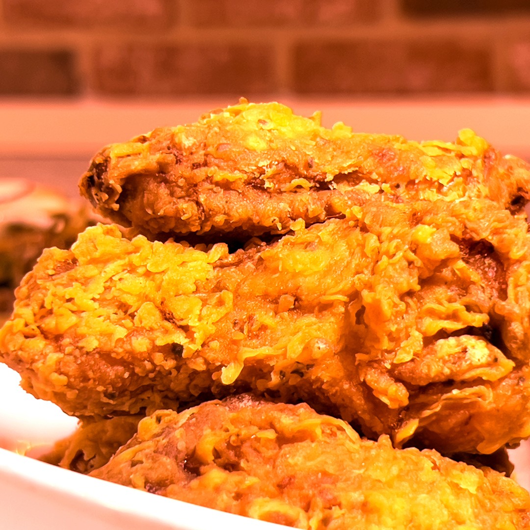 Close-up of Koreanz signature crispy fried chicken and sweet-spicy wings, garnished with sesame seeds and green onions, served with dipping sauce and pickled radish. Showcasing authentic Korean comfort food.