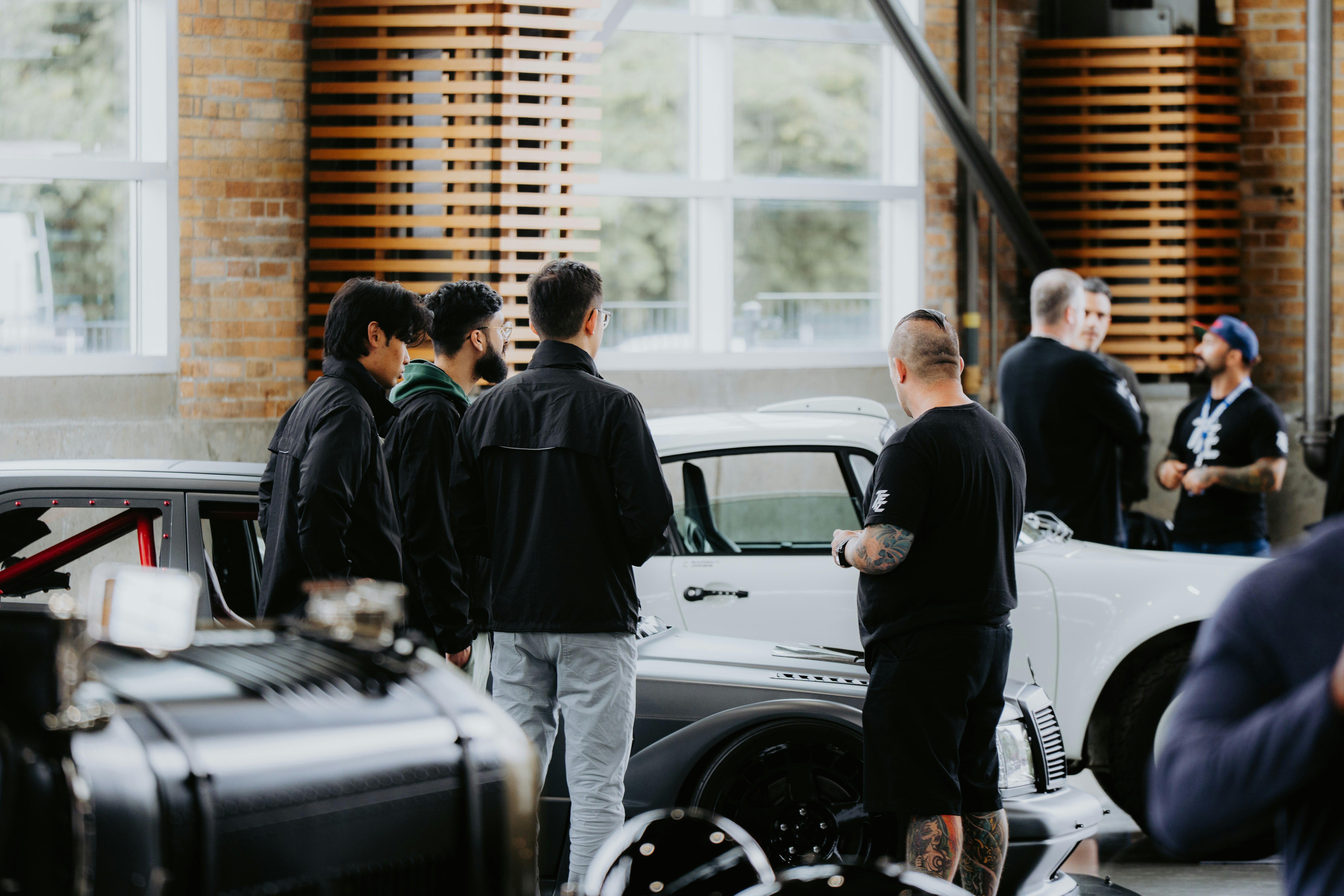 Car people standing around cars, mechanics, social gathering, cars and coffee vibe, detail orientated maintenance team