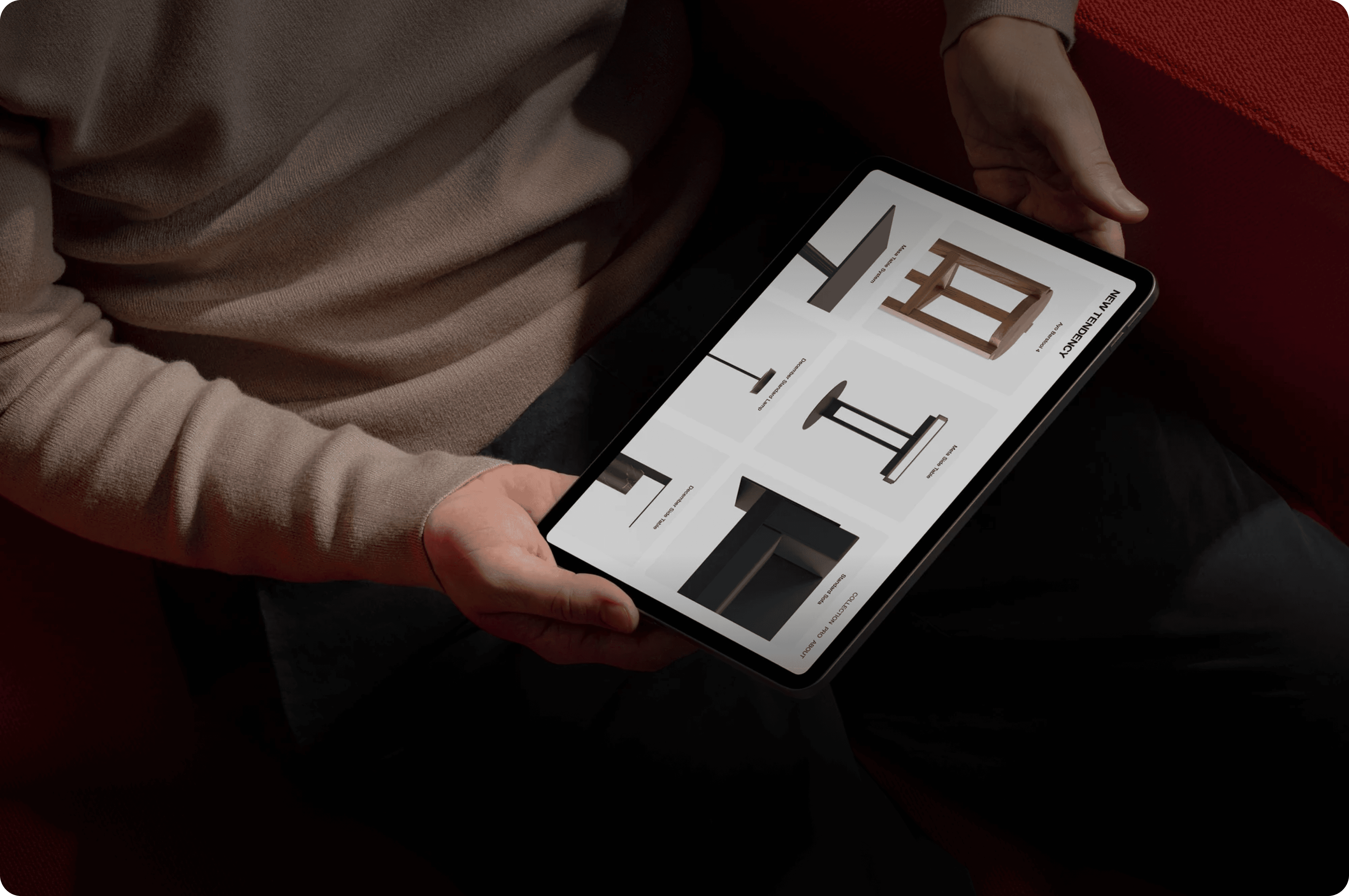 Person holding an iPad Pro mockup displaying a furniture catalog website design