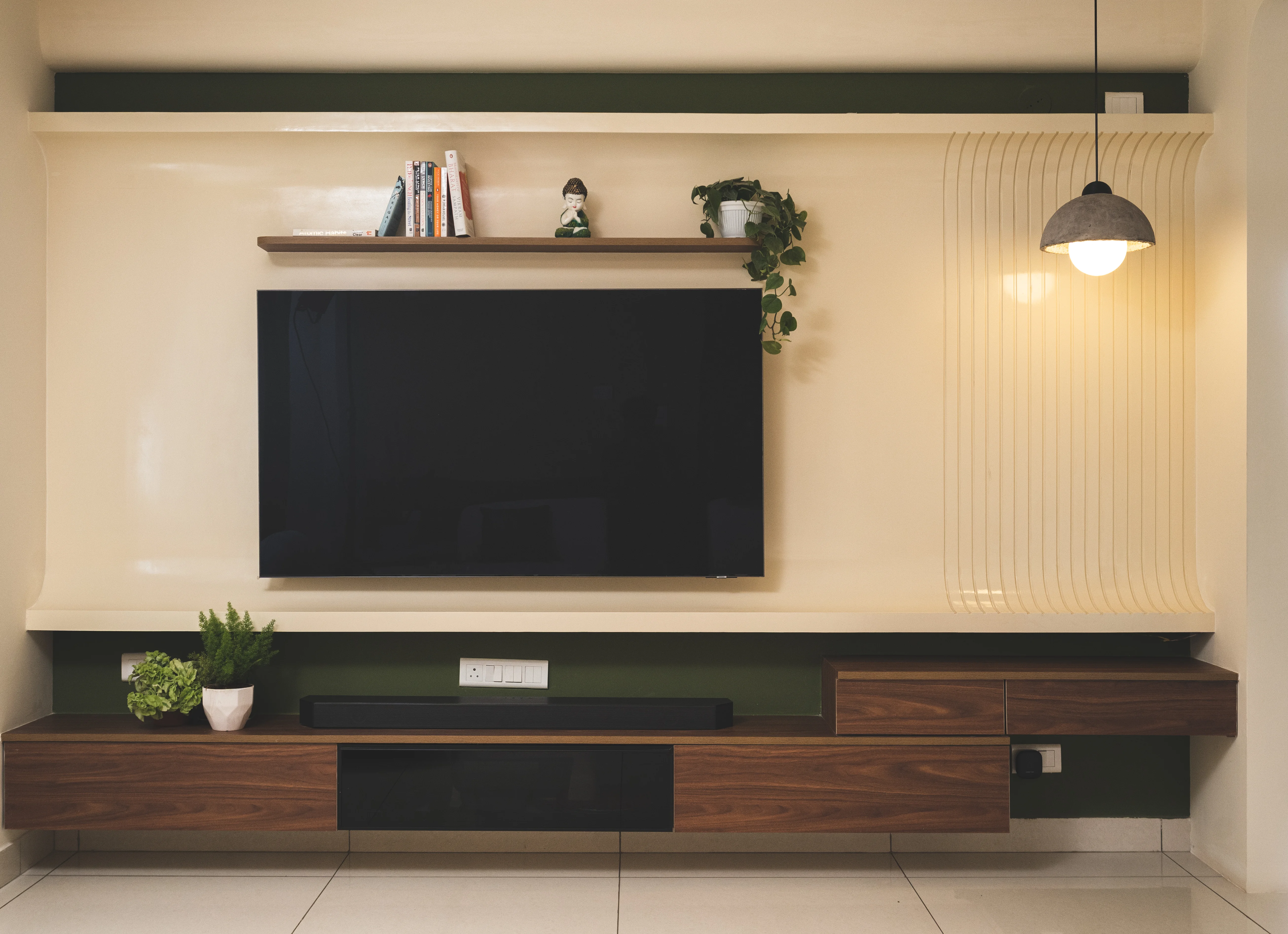 A modern living room featuring a flat screen TV, showcasing curved, minimalistic design elements for South Indian homes.