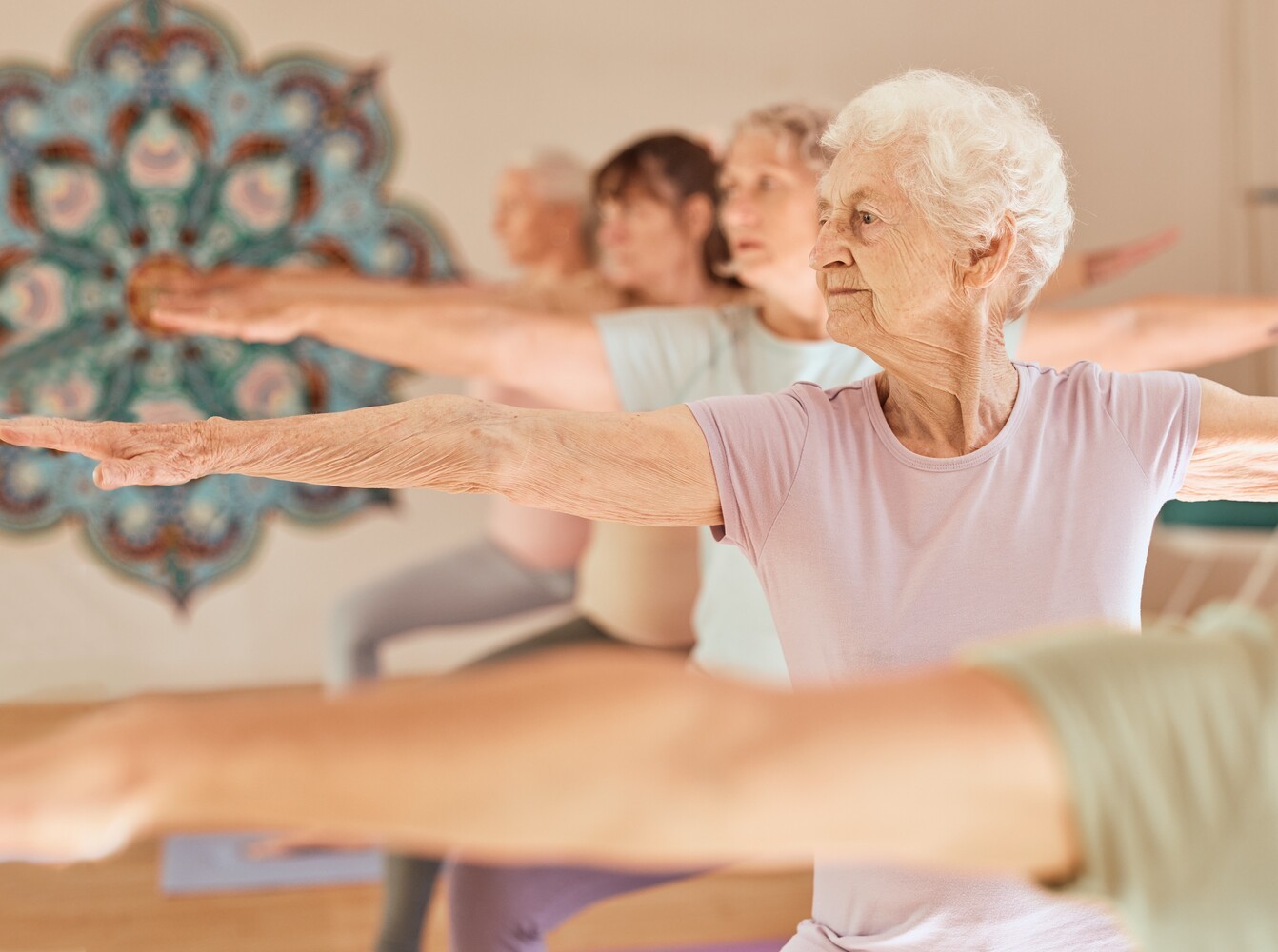 group of elderly women doing gentle yoga exercises for weight loss during a class for fitness and mobility