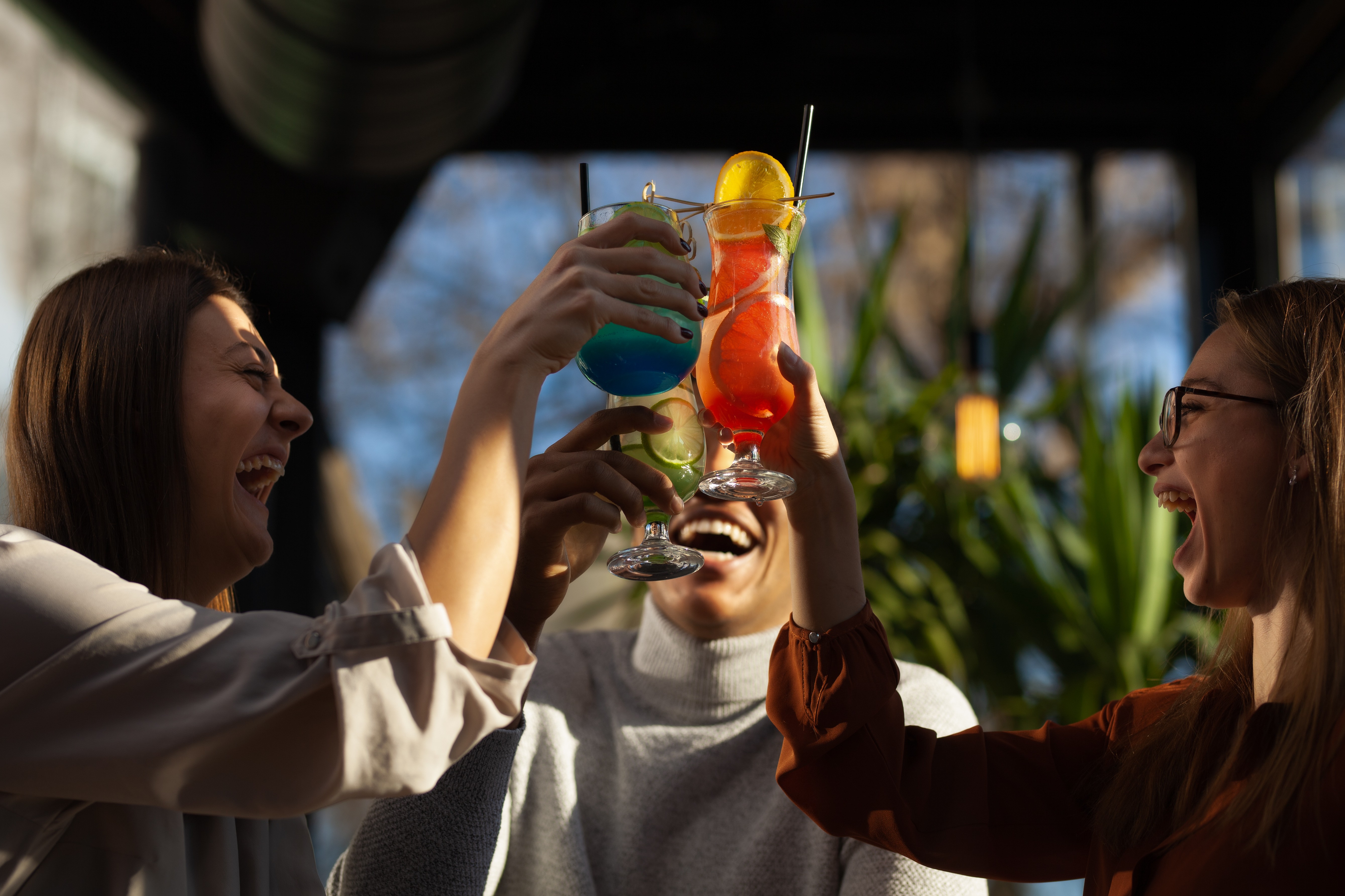 A circle of people sitting cross-legged, meditating with hands in a prayer position. Soft, warm lighting.
