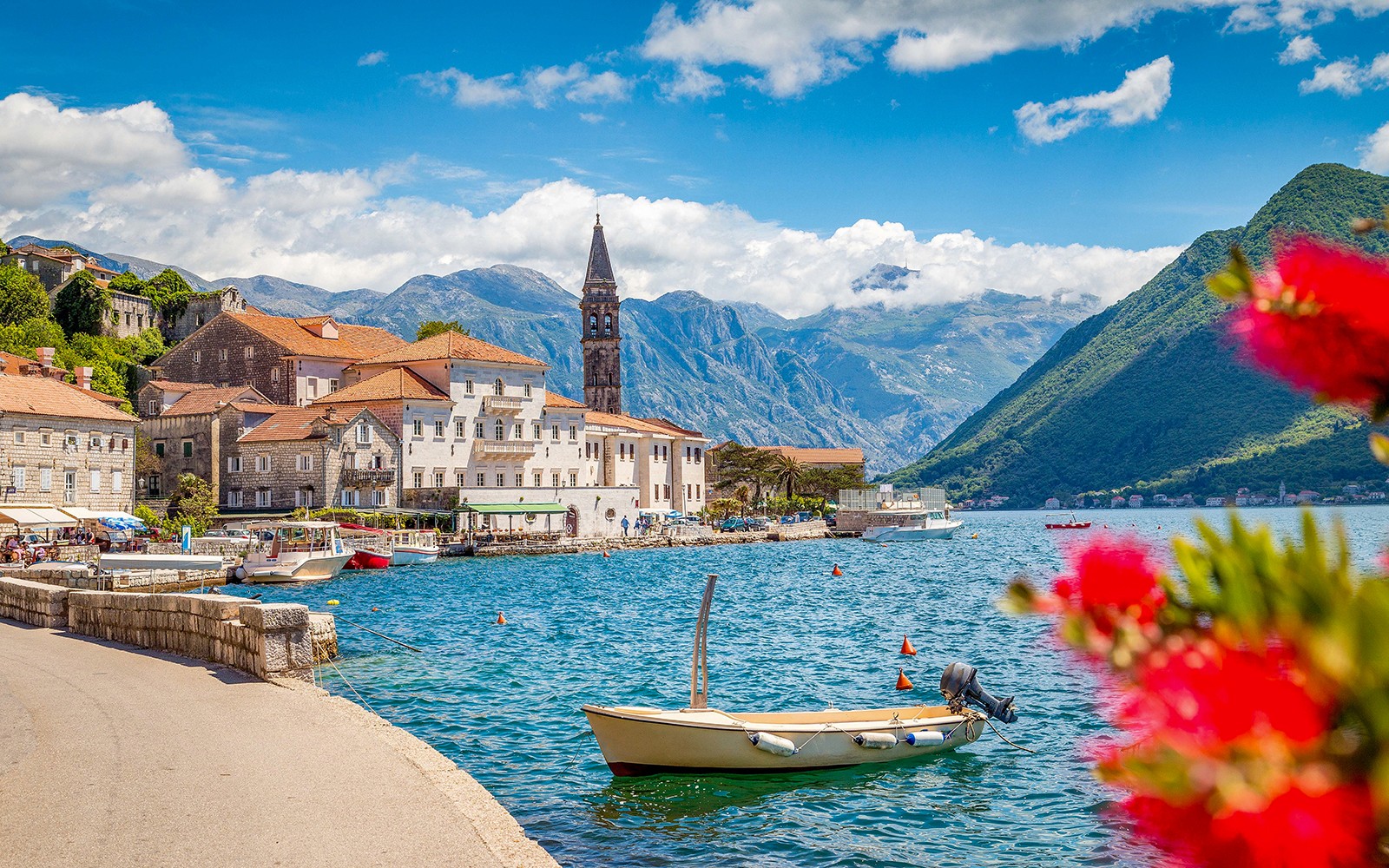 Perast old town waterfront with boats and mountains in Montenegro.