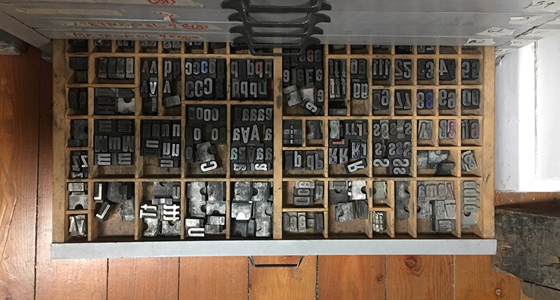 Different metal letters used for the press benches are stored in a drawer.