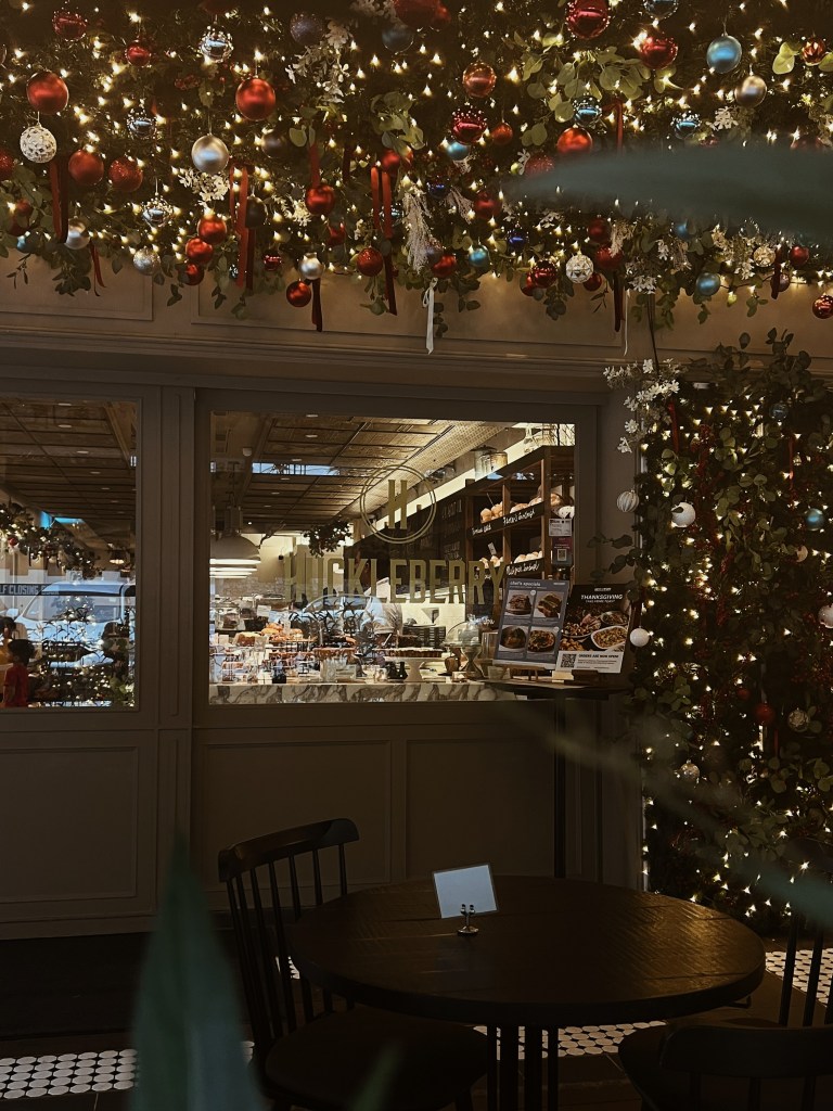 Decorated entrance of Huckleberry restaurant with festive lights and ornaments, showcasing a warm holiday atmosphere.